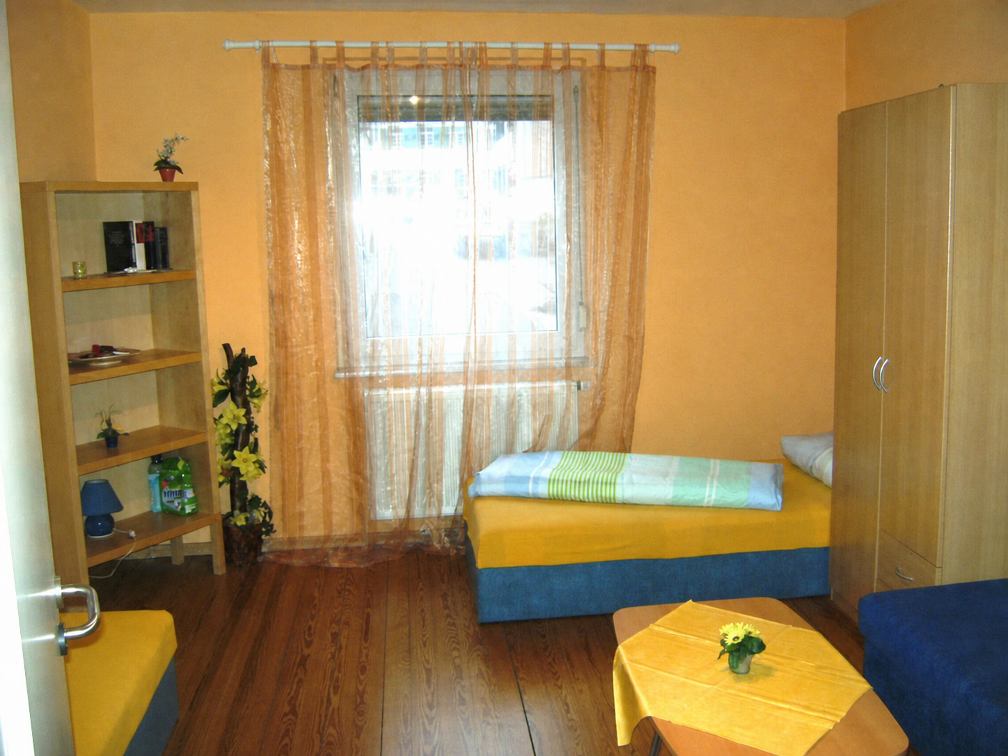 Apartmentzimmer mit Bett, Tisch und Fenster