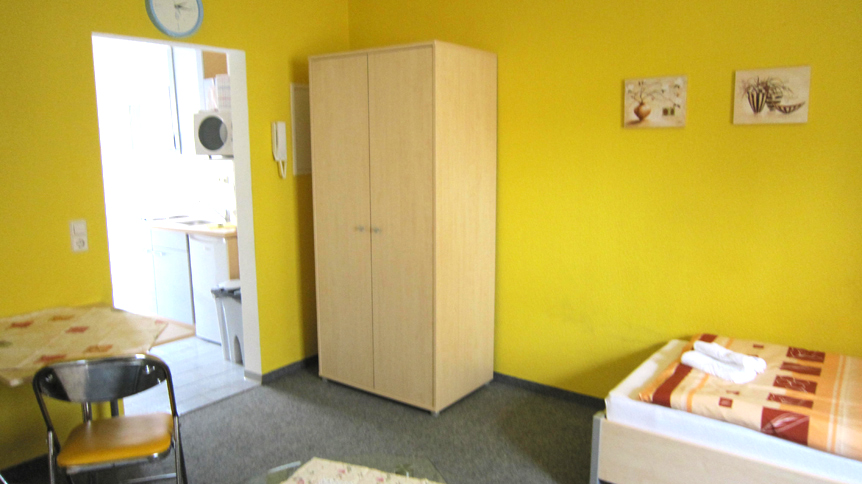 Einzelbettzimmer mit Schrank und Küchenzugang